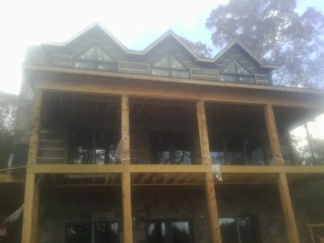 Dormers and porch framing on a large log home under construction — Roof Coating work by our crew in Jerico Springs