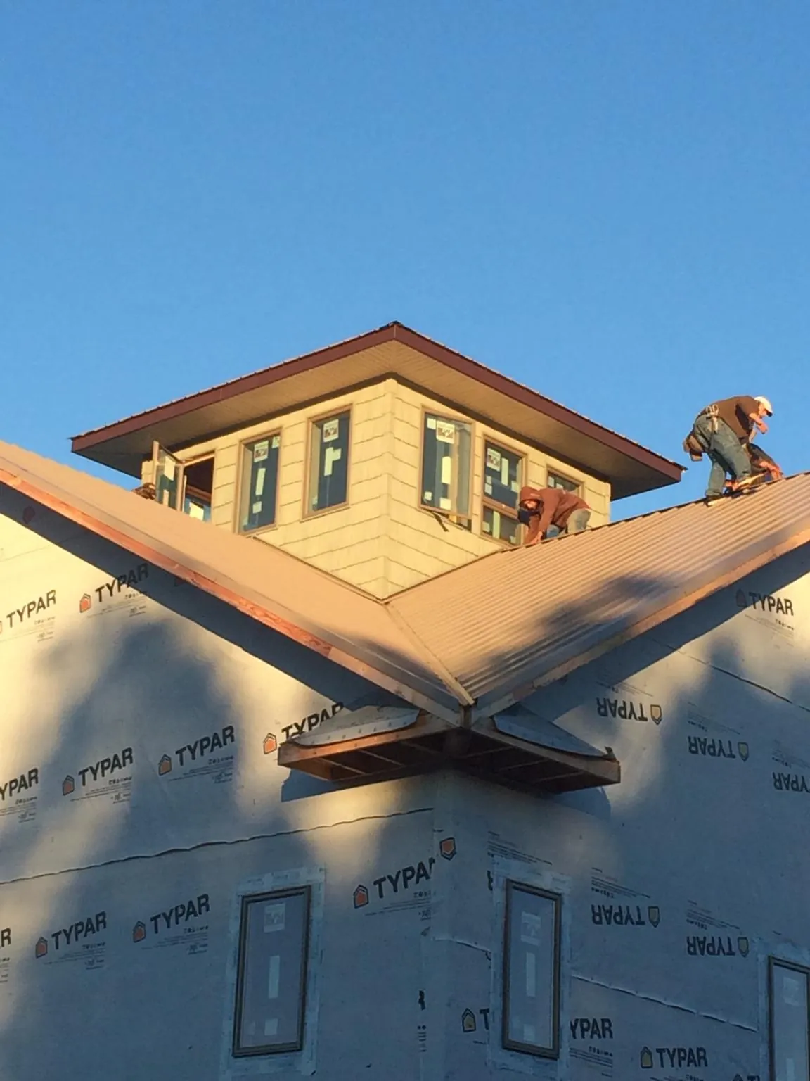 Roofers working around a rooftop cupola on a new metal roof at sunset — Roof Waterproofing in Jerico Springs by Roofing Brothers